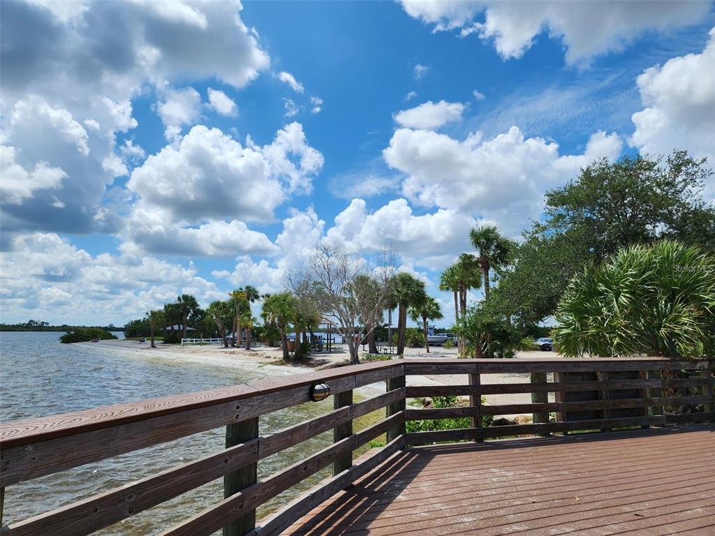 A wooden deck overlooks a sandy beach with palm trees and a cloudy blue sky — 20339 BACHMANN BOULEVARD, PORT CHARLOTTE, FL