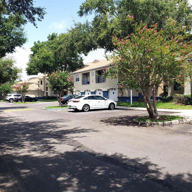A white sedan is parked in front of a multi-story apartment building with trees — 7280 WESTPOINTE BOULEVARD UNIT 831, ORLANDO, FL