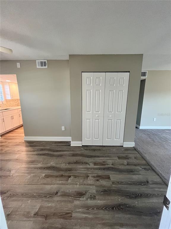 A room with wood-look flooring, a white bi-fold closet, and a view into a kitchen — 2727 75TH STREET W UNIT 7A14, BRADENTON, FL