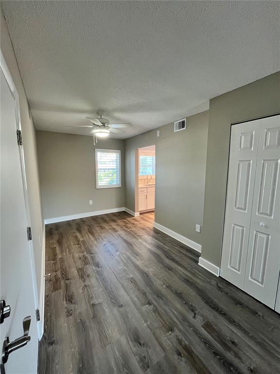 A room with wood-look flooring, a ceiling fan, and a doorway leading to a kitchen — 2727 75TH STREET W UNIT 7A14, BRADENTON, FL