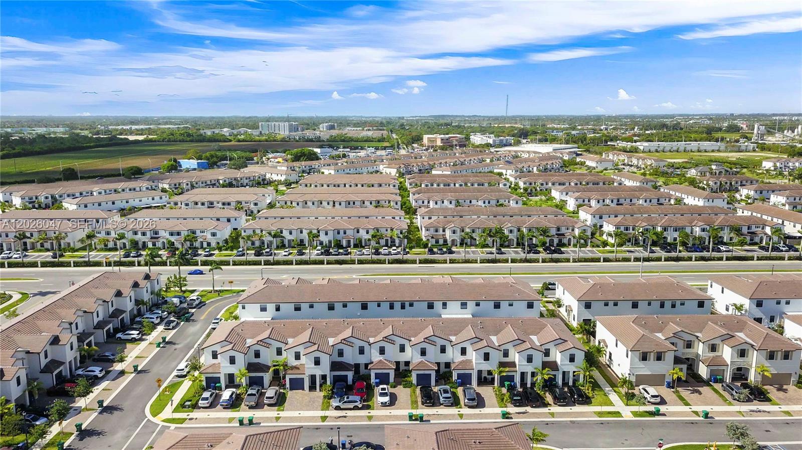 An aerial view shows rows of modern townhouses with brown roofs and paved driveways — 12862 SW 231st St, Miami FL 33170, MIAMI, FL
