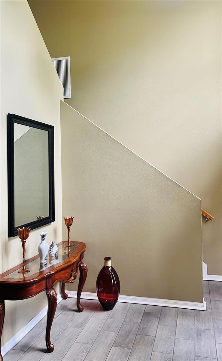 A foyer features a wooden console table, a wall mirror, and a staircase with beige walls — 184 Massini Avenue NW, Palm Bay FL 32907, PALM BAY, FL