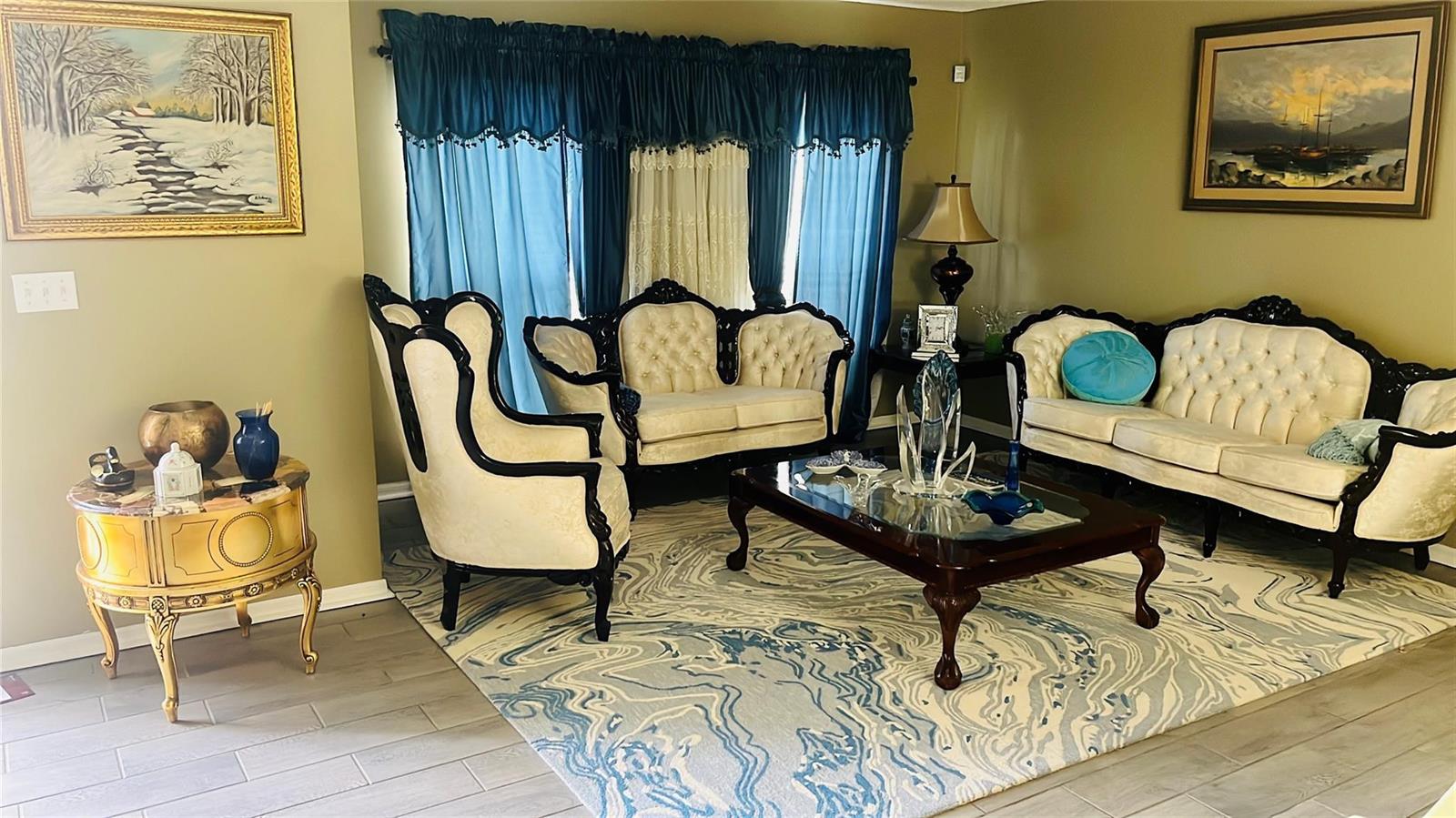 A living room features ornate cream-colored furniture, a glass-topped coffee table, and a blue-patterned rug — 184 Massini Avenue NW, Palm Bay FL 32907, PALM BAY, FL