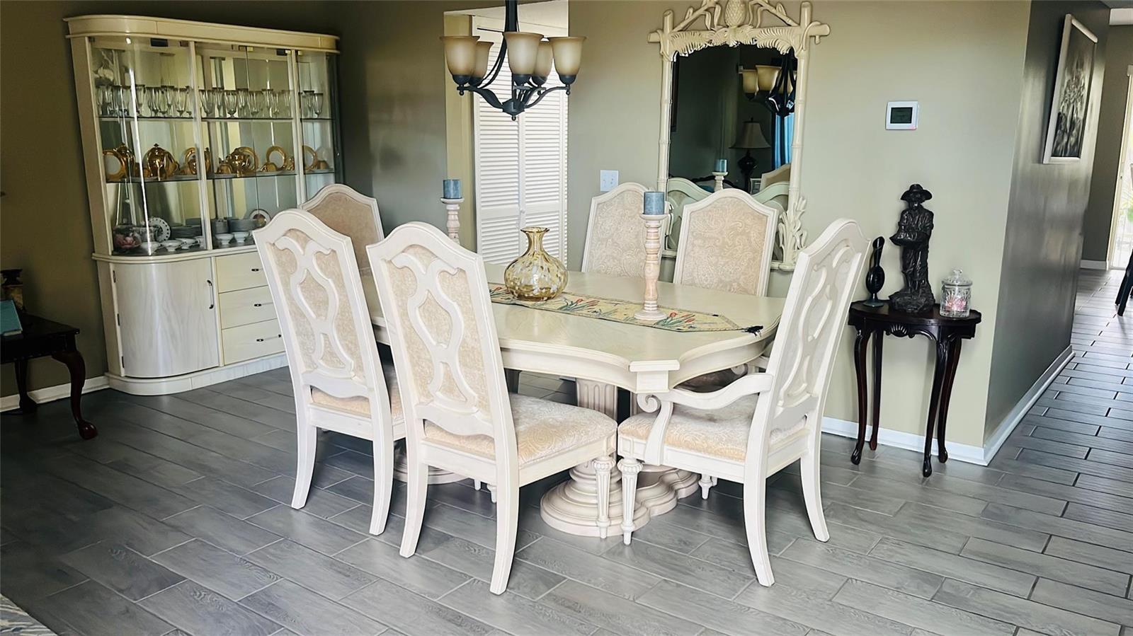 A dining room features a light-colored table and chairs, a matching china cabinet, and mirror — 184 Massini Avenue NW, Palm Bay FL 32907, PALM BAY, FL
