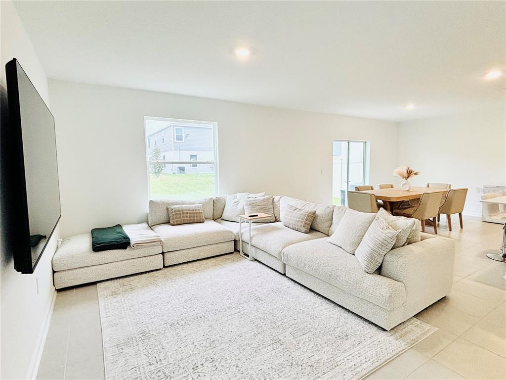 A living room with a large sectional sofa, a rug, and an adjacent dining area — 4045 OLD MILL ROAD, HAINES CITY, FL