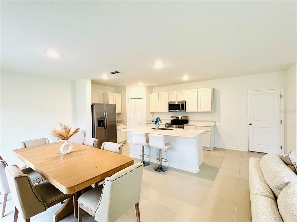 An open-concept kitchen and dining area features white cabinetry, a central island, and tile flooring — 4045 OLD MILL ROAD, HAINES CITY, FL