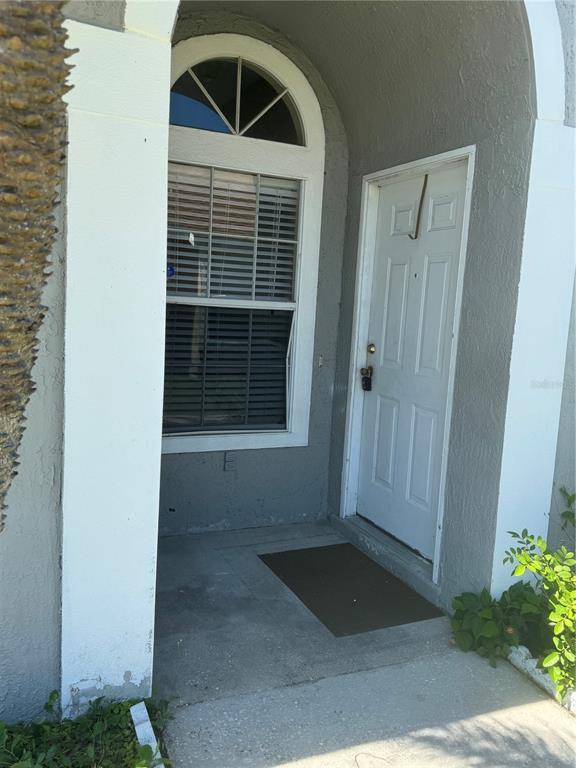 A white front door and an arched window with blinds are set in a gray entryway — 2399 HARBOR TOWN DRIVE, KISSIMMEE, FL