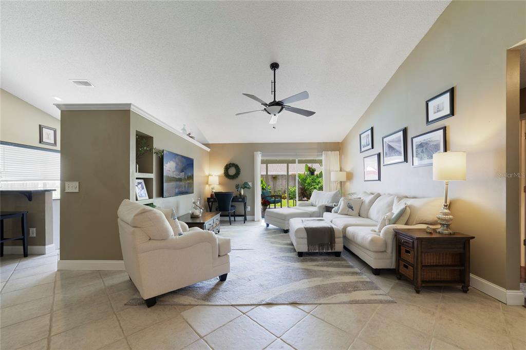 A living room features a vaulted ceiling, tile flooring, a sectional sofa, and a ceiling fan — 504 WEXDON COURT, LAKE MARY, FL