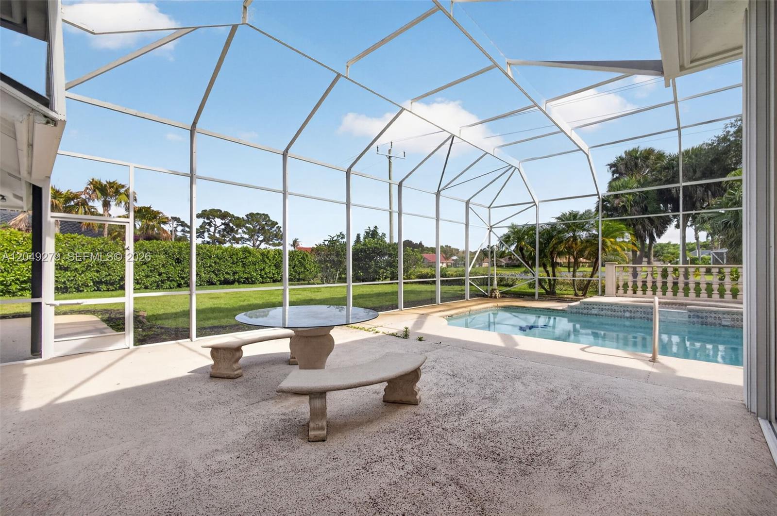 A screened-in patio features a concrete floor, a stone table with benches, and a swimming pool — 19558 Red Gum Trl, Jupiter FL 33458, JUPITER, FL