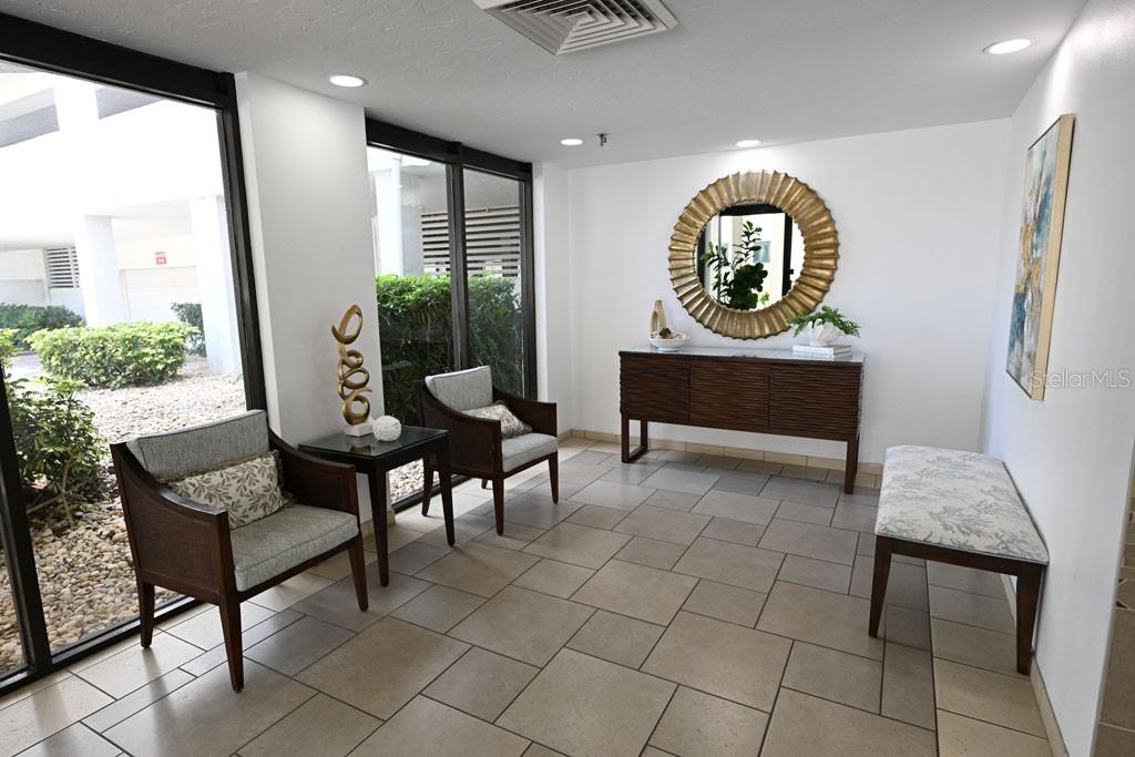 A lobby features tiled floors, two armchairs, a bench, a console table, and a mirror — 1100 BENJAMIN FRANKLIN DRIVE UNIT 502, SARASOTA, FL