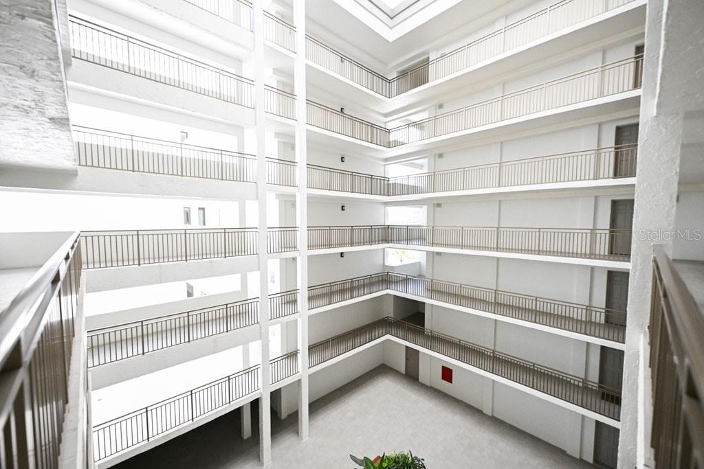 An interior view of a multi-story apartment building atrium with open-air balconies and railings — 1100 BENJAMIN FRANKLIN DRIVE UNIT 502, SARASOTA, FL
