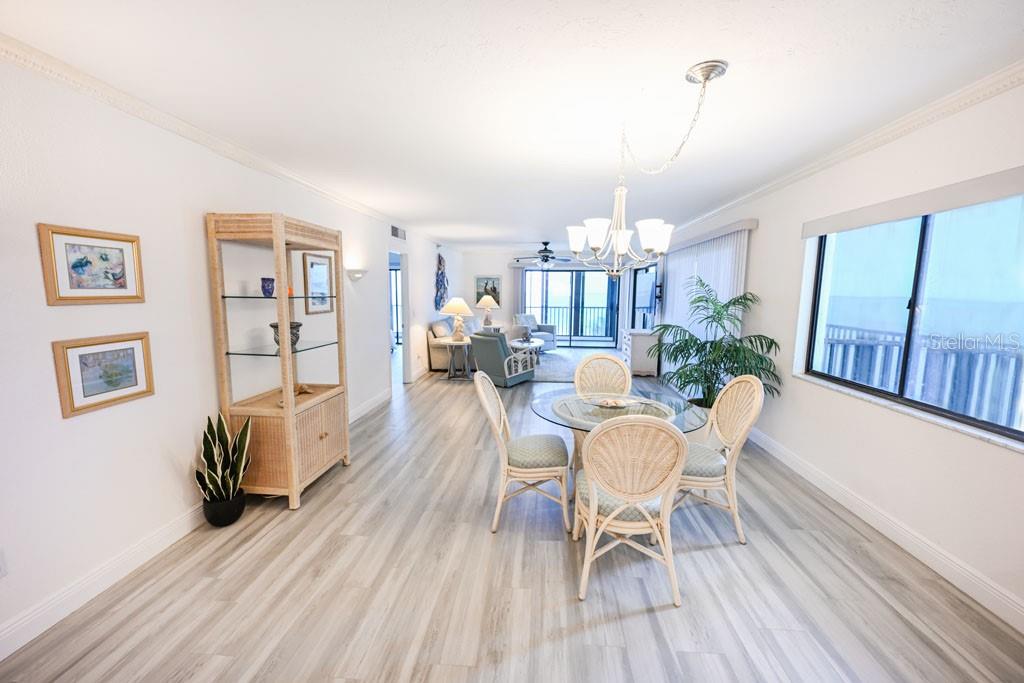 A dining area with a glass table and wicker chairs sits before a living room — 1100 BENJAMIN FRANKLIN DRIVE UNIT 502, SARASOTA, FL