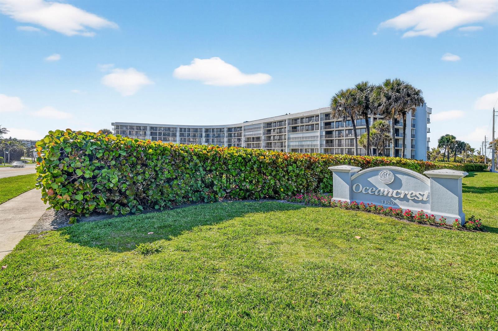 A large, curved multi-story apartment building stands behind a hedge and a stone entrance sign — 1300 S Highway A1a # 320, Jupiter FL 33477, JUPITER, FL
