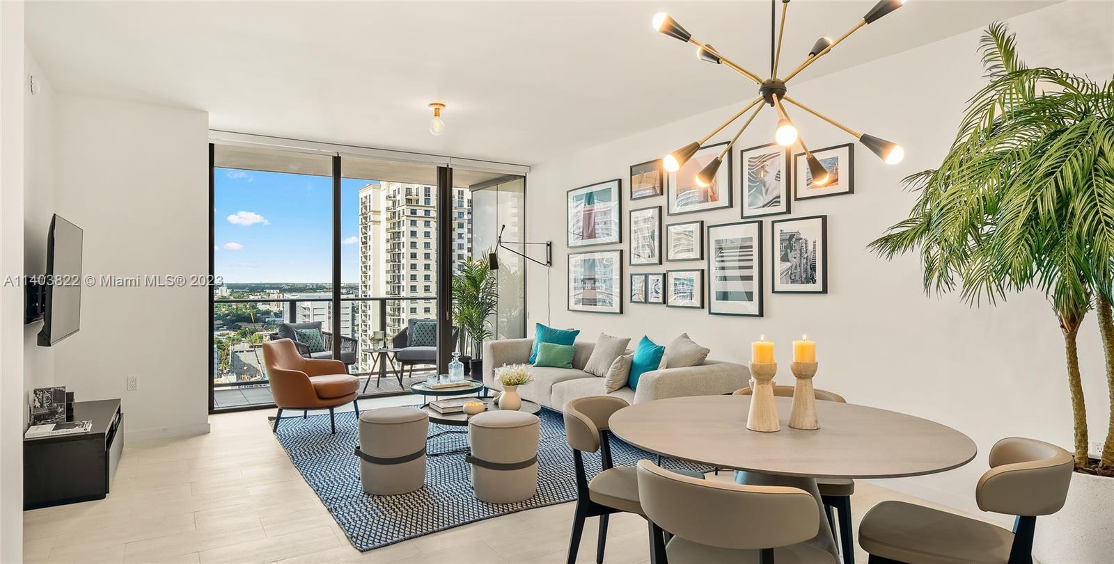A modern living and dining area features a balcony, gallery wall, and contemporary light fixture — 1000 Brickell Plaza # 2711, Miami FL 33131, MIAMI, FL