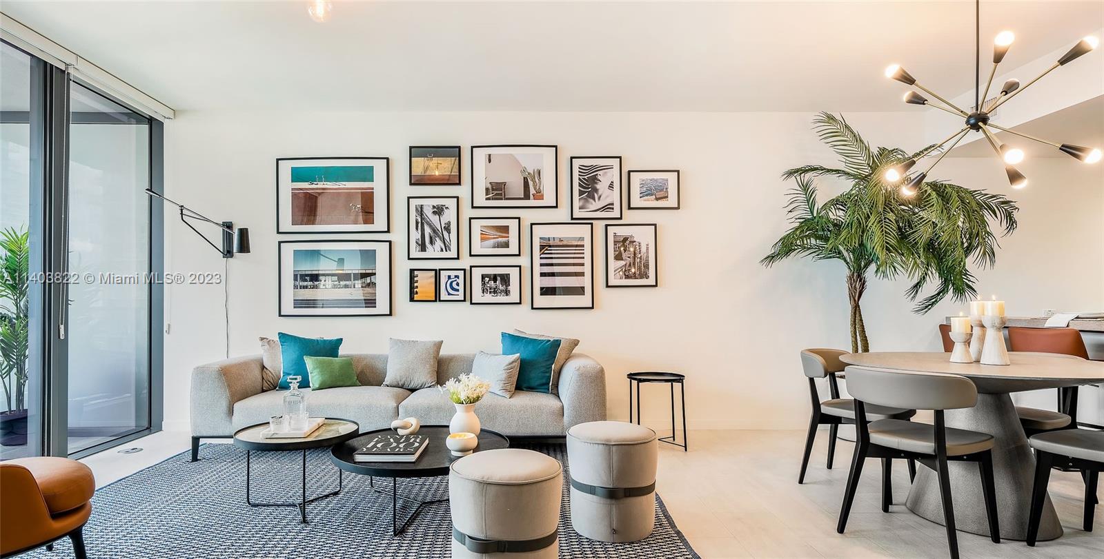 A modern living and dining area features a gallery wall, gray sofa, and palm tree — 1000 Brickell Plaza # 2711, Miami FL 33131, MIAMI, FL