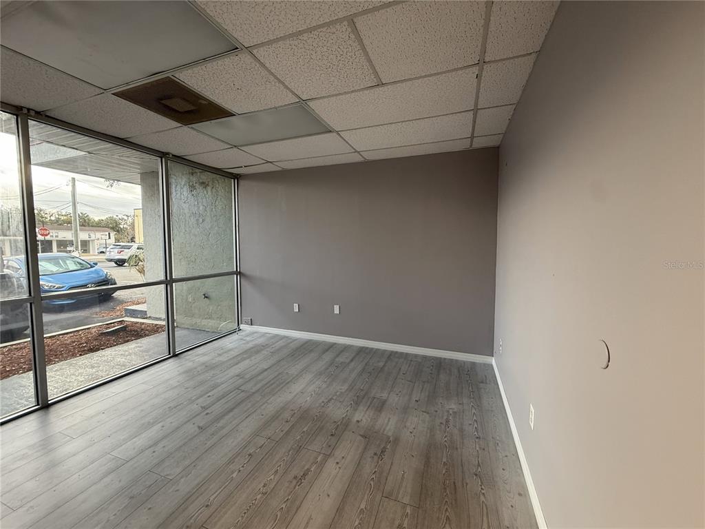 An empty office space features light wood-look flooring, gray walls, and large floor-to-ceiling windows — 2007 W KENNEDY BOULEVARD UNIT A, TAMPA, FL