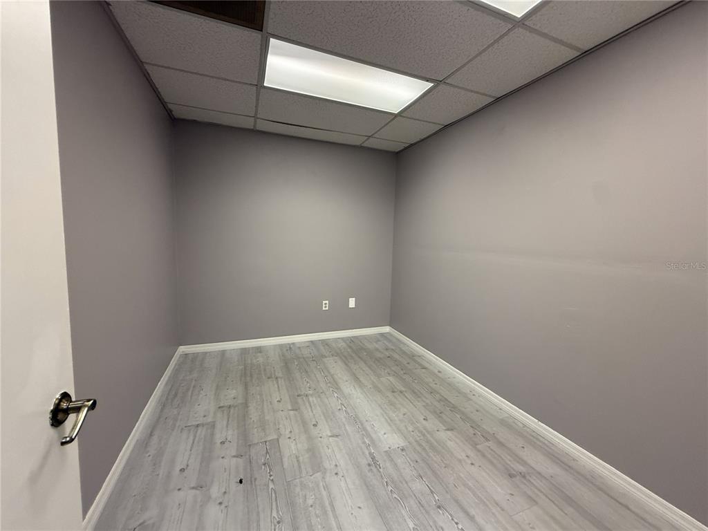 An empty office room features gray walls, light wood-look flooring, and a drop ceiling — 2007 W KENNEDY BOULEVARD UNIT A, TAMPA, FL