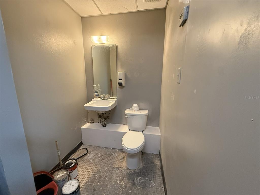 A small, unfinished bathroom features a wall-mounted sink, a toilet, and gray painted walls — 2007 W KENNEDY BOULEVARD UNIT A, TAMPA, FL