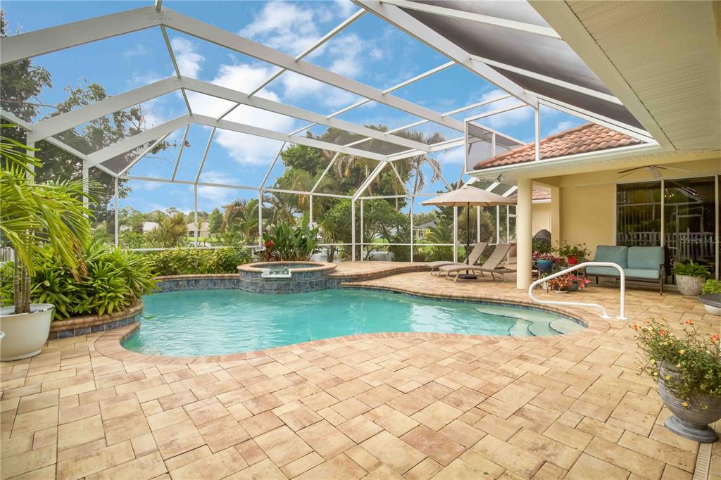 A screened-in patio features a swimming pool, a raised spa, and light-colored stone pavers — 11109 28TH STREET CIRCLE E, PARRISH, FL