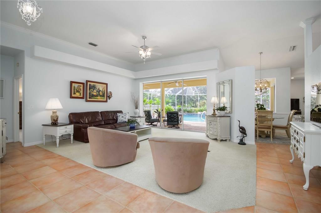 A living room features tile floors, a beige area rug, and sliding doors to a pool — 11109 28TH STREET CIRCLE E, PARRISH, FL