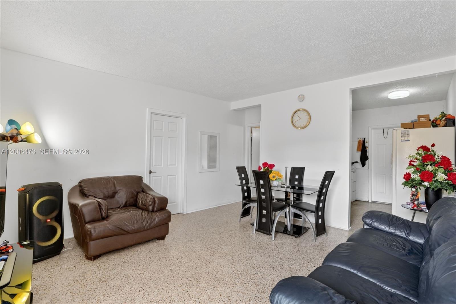 A living and dining area features a brown leather chair, a dark sofa, and terrazzo flooring — 2110 NW 24th St, Miami FL 33142, MIAMI, FL