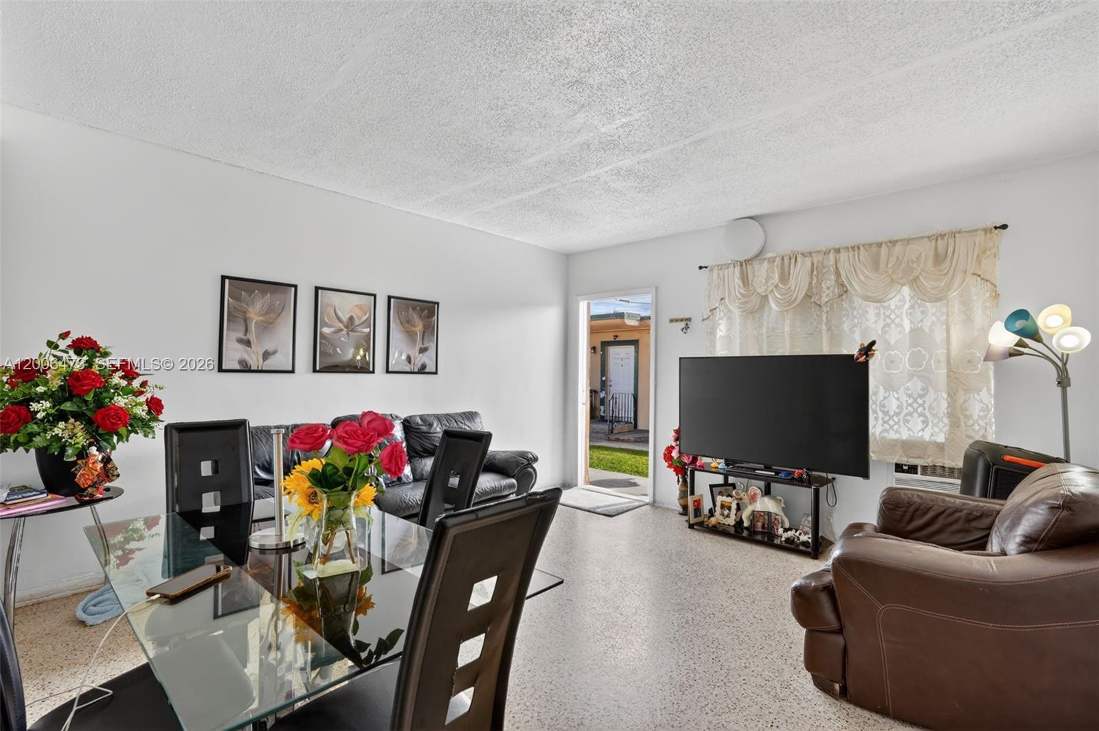 A living and dining area features a glass table, leather furniture, and a television — 2110 NW 24th St, Miami FL 33142, MIAMI, FL