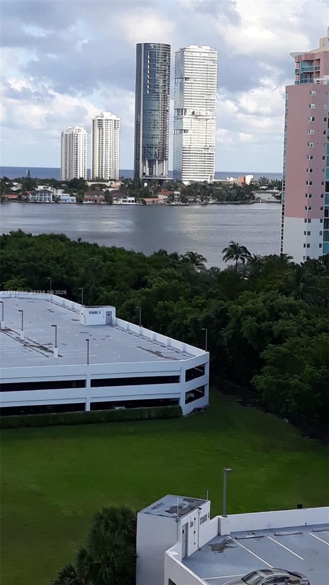 An elevated view shows a parking garage, green space, and high-rise buildings near water — AVENTURA, FL
