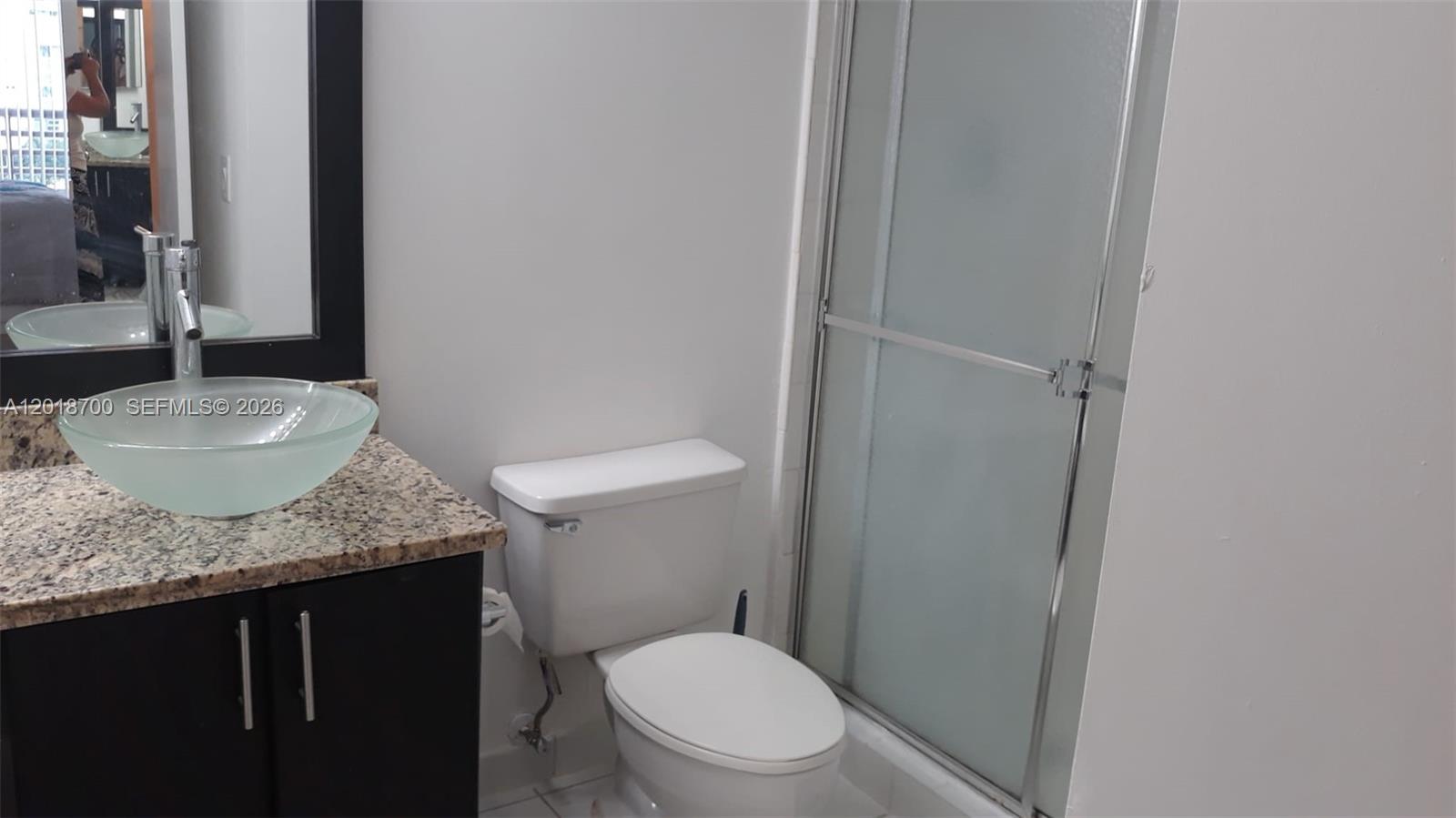 A bathroom features a glass vessel sink on a granite vanity and a shower stall — AVENTURA, FL