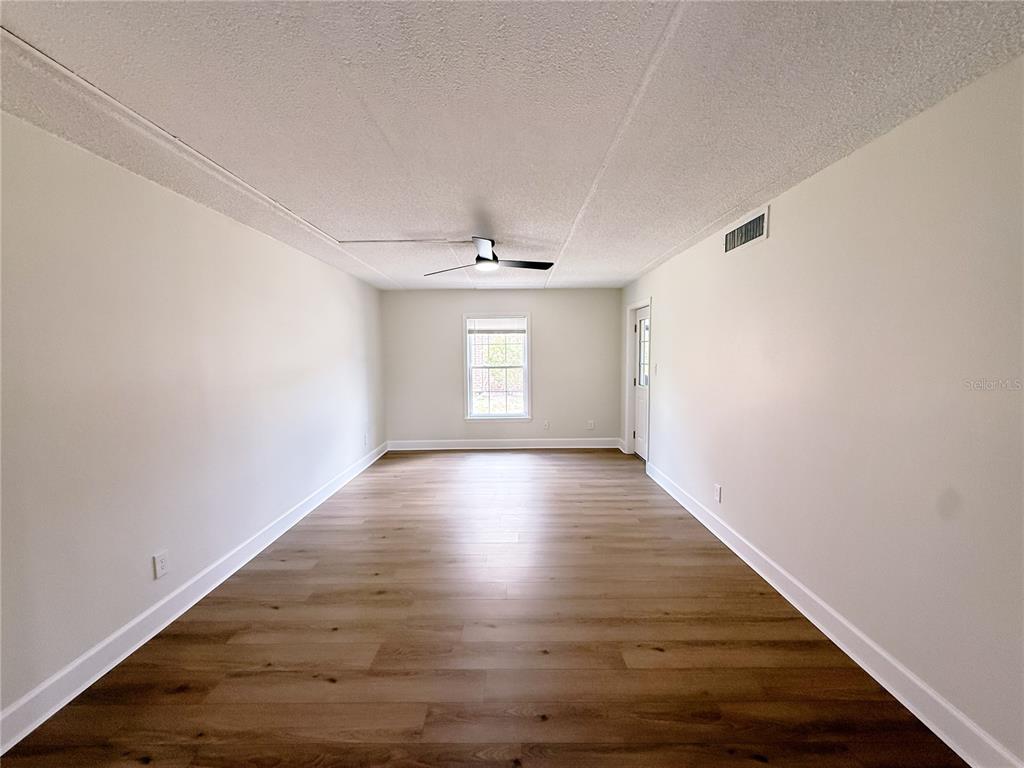 An empty room features light-colored walls, wood-look flooring, a ceiling fan, and one window — 1275 85TH AVENUE UNIT 1275B, ST PETERSBURG, FL