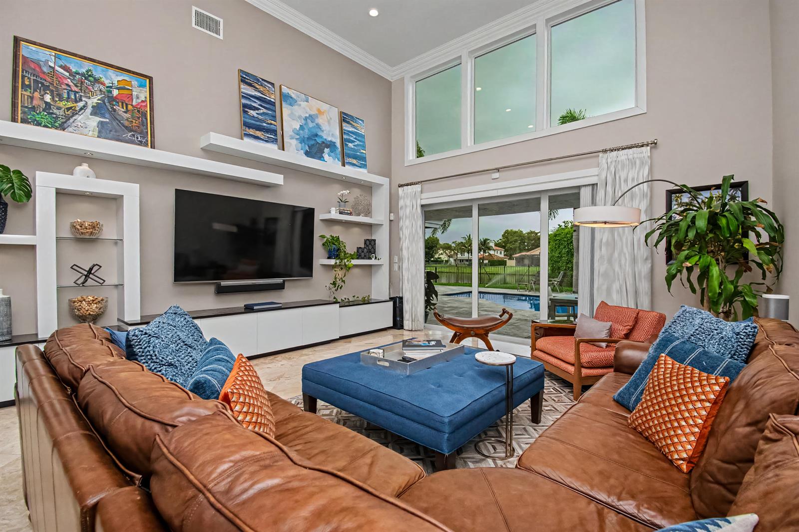 A living room features a large leather sectional, blue ottoman, wall-mounted television, and floor-to-ceiling windows — 2653 NW 46th Street, Boca Raton FL 33434, BOCA RATON, FL