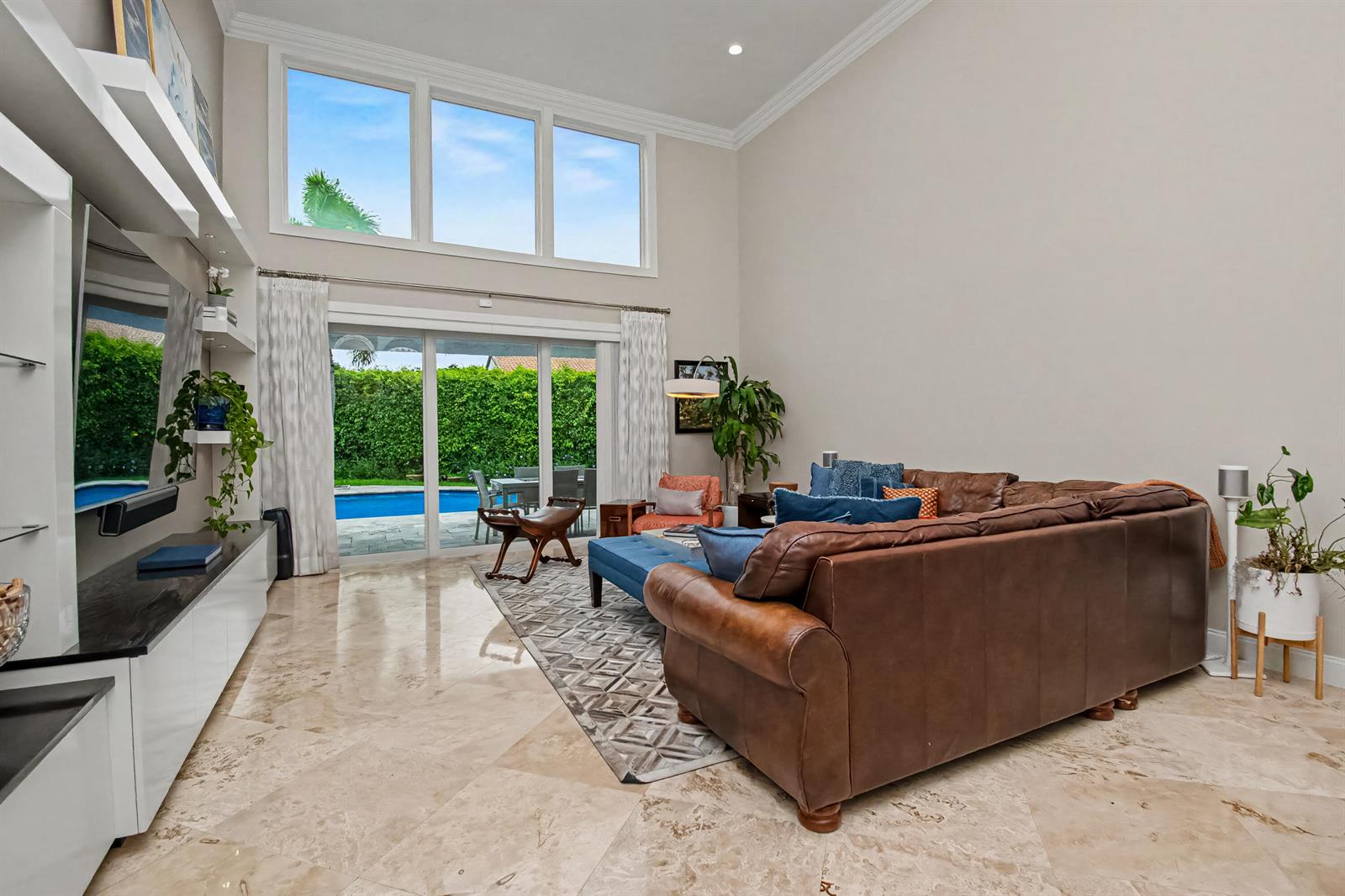 A living room with high ceilings, a brown leather sectional, and sliding doors to a pool — 2653 NW 46th Street, Boca Raton FL 33434, BOCA RATON, FL