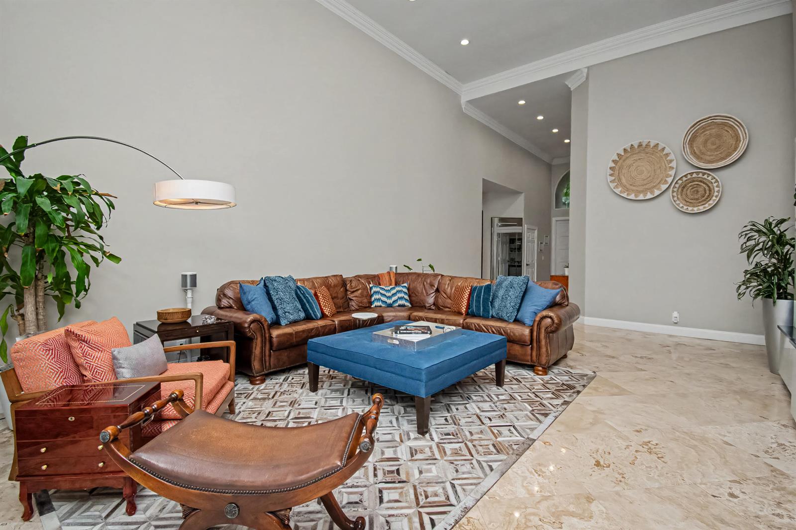 A spacious living room features a leather sectional, blue ottoman, and high vaulted ceilings — 2653 NW 46th Street, Boca Raton FL 33434, BOCA RATON, FL