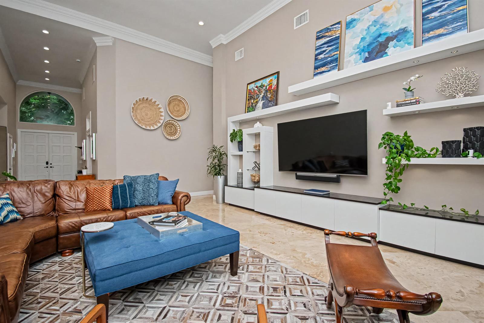 A living room features a large leather sofa, blue ottoman, and a wall-mounted television unit — 2653 NW 46th Street, Boca Raton FL 33434, BOCA RATON, FL