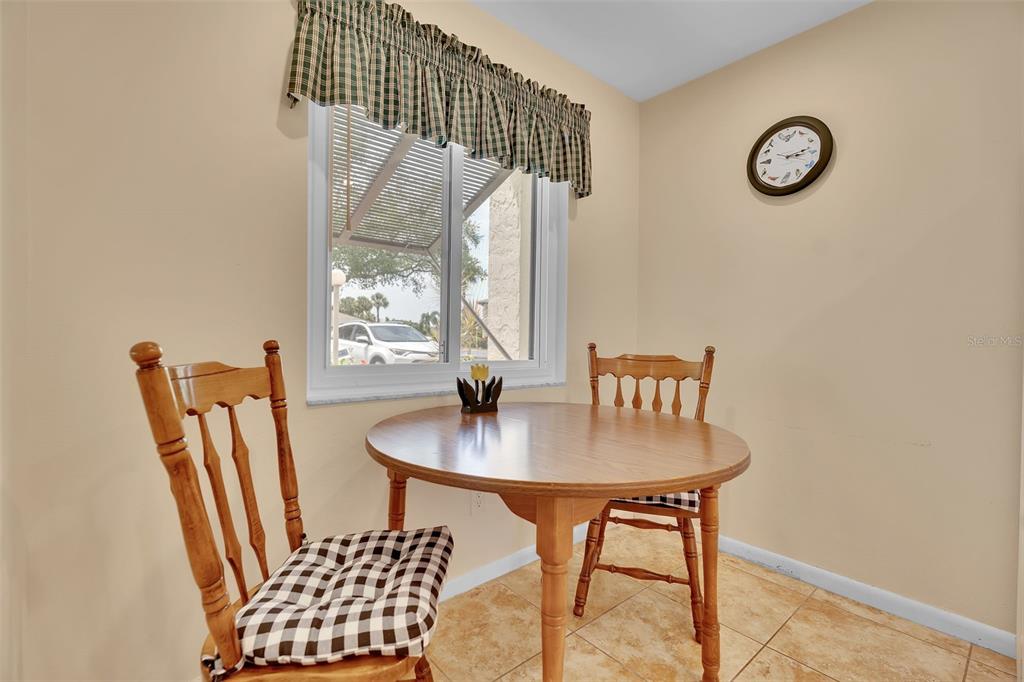 A small dining area features a round wooden table, two chairs, and a window — 4644 LONGWATER UNIT 97, SARASOTA, FL