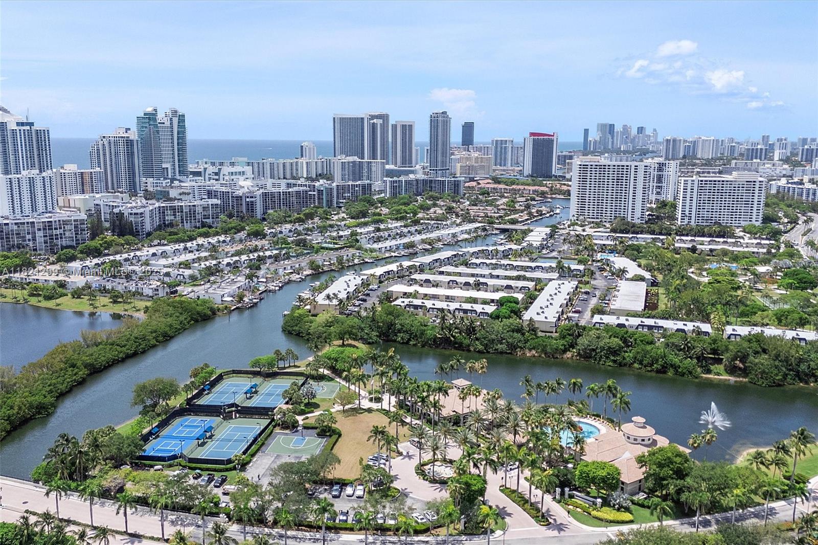 An aerial view shows a residential complex with tennis courts, a pool, and a waterway — 1382 Harbor Vw W, Hollywood FL 33019, HOLLYWOOD, FL
