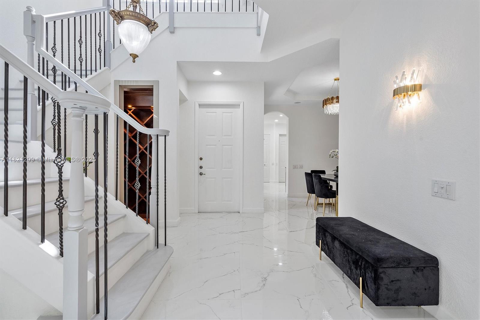 A bright foyer features white marble floors, a staircase with iron railings, and a black bench — 1382 Harbor Vw W, Hollywood FL 33019, HOLLYWOOD, FL