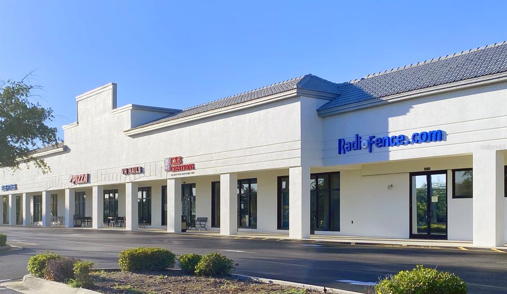 A single-story commercial strip mall with white stucco walls and several storefronts under a roof — 1125,1127,1131 BAL HARBOR BOULEVARD UNIT 1125, PUNTA GORDA, FL
