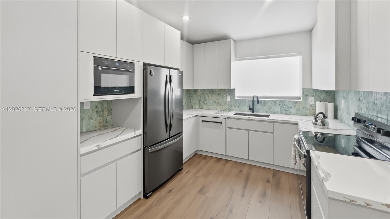 A modern kitchen features white flat-panel cabinets, stainless steel appliances, and a patterned backsplash — MIAMI, FL