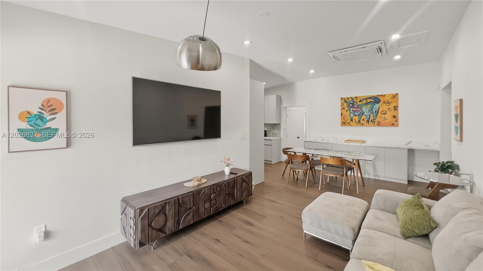 A modern living room features a television, wooden media console, dining area, and sofa — MIAMI, FL