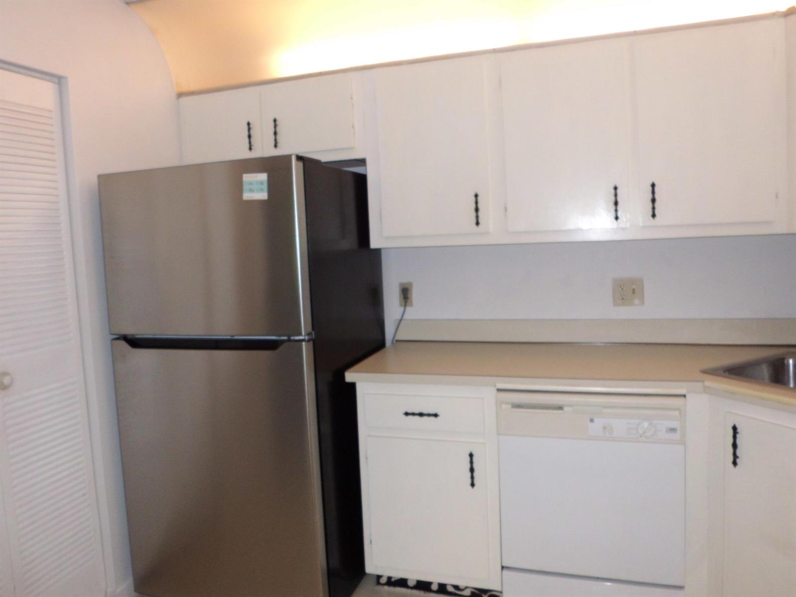 A kitchen features white cabinets, a stainless steel refrigerator, a dishwasher, and a countertop — 121 Lake Pine Circle # 2, FL 33463, FL