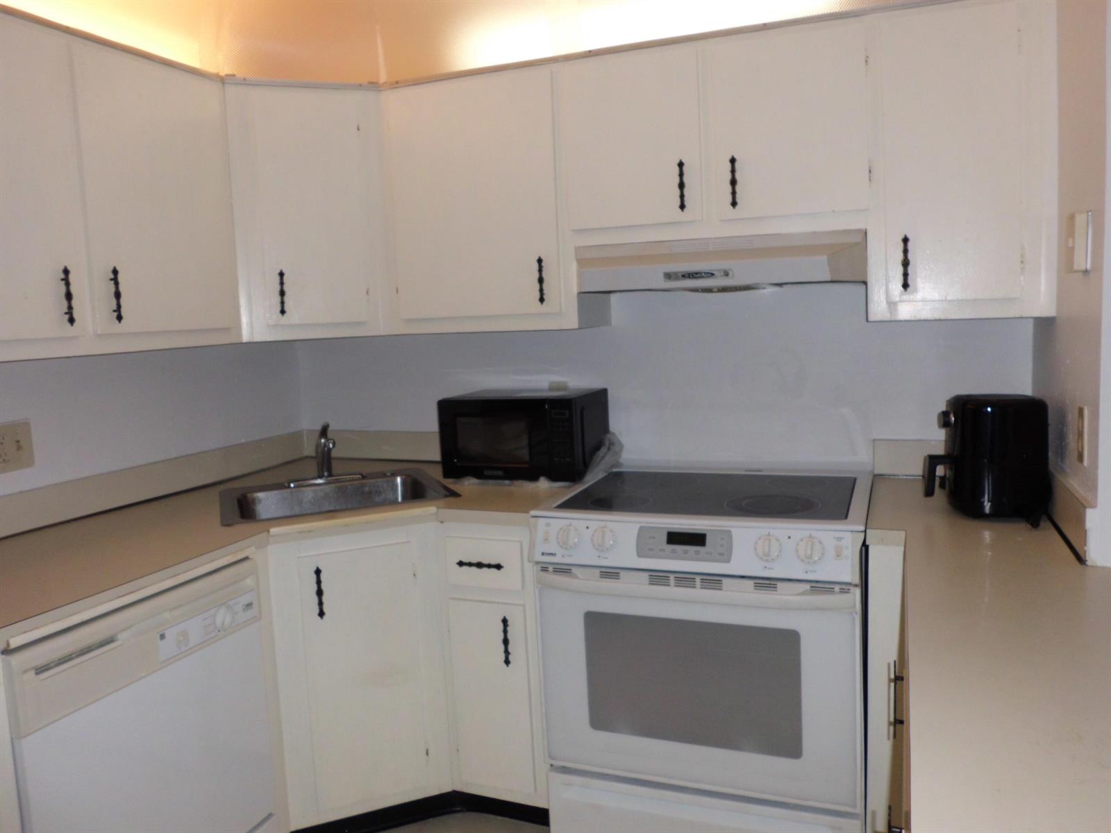 A kitchen features white cabinets, a stainless steel sink, a microwave, and a white stove — 121 Lake Pine Circle # 2, FL 33463, FL