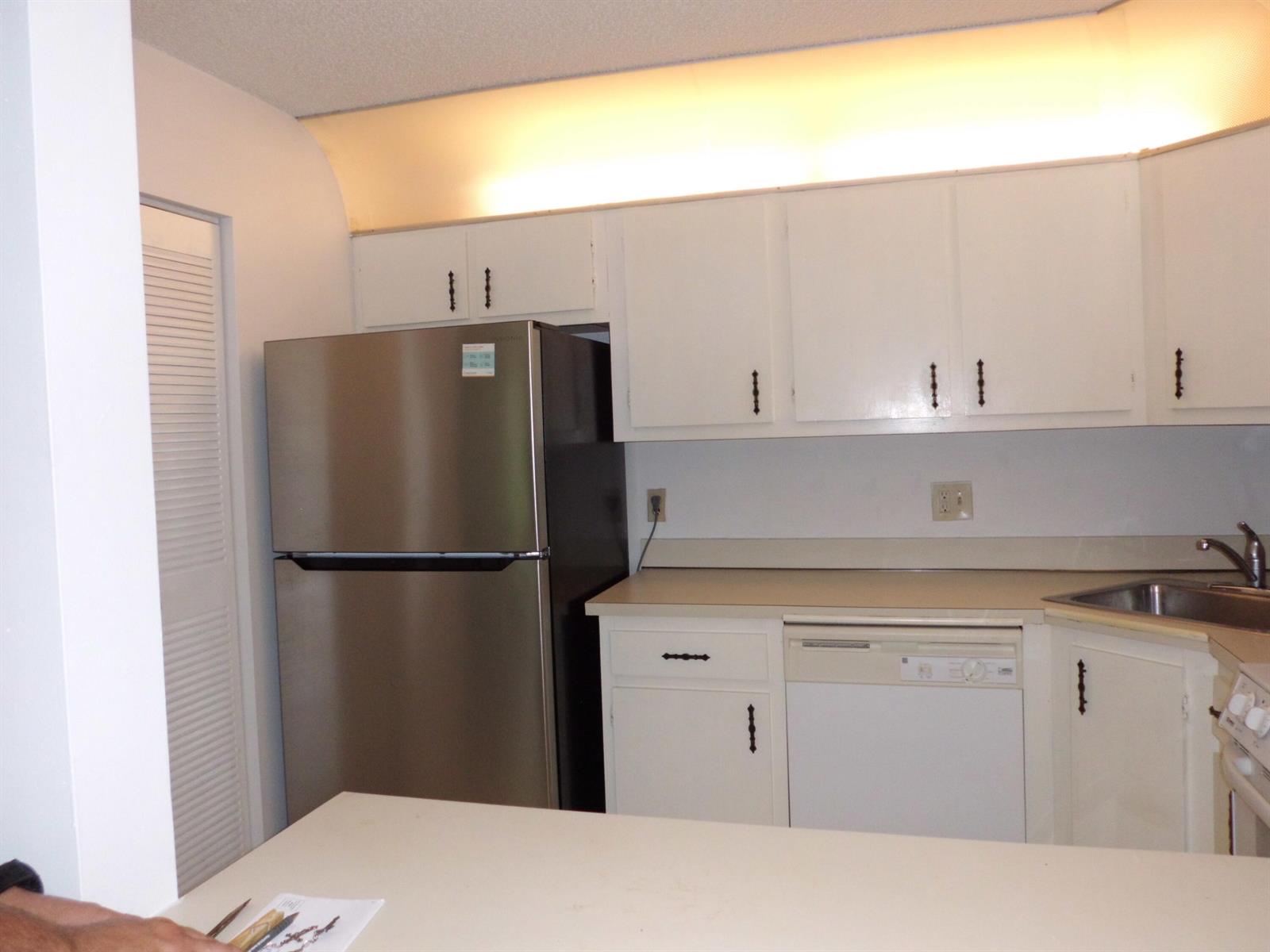 A kitchen features white cabinets, a stainless steel refrigerator, a dishwasher, and a sink — 121 Lake Pine Circle # 2, FL 33463, FL
