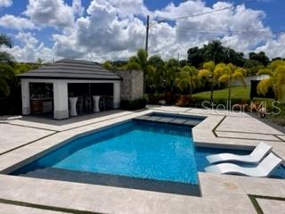 A swimming pool with lounge chairs sits next to a covered outdoor kitchen and patio — Lot 8 PR-159 Km 1.9 Inter BO. UNIBON, MOROVIS, PR