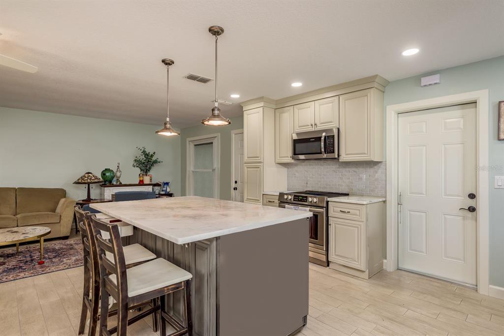 A kitchen with a large island, stainless steel appliances, and cream-colored cabinetry — 3305 GORSE COURT, PALM HARBOR, FL
