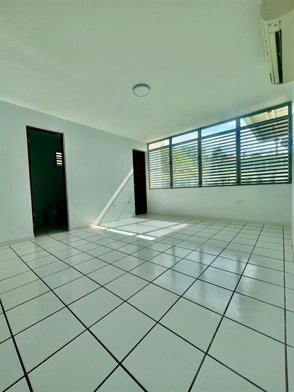 An empty room with white tiled floors, light walls, and a large window with blinds — YAMIL GALIB PASEO LOS ROBLES UNIT 1614, MAYAGUEZ, PR