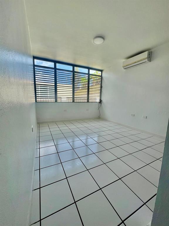 An empty room features white tiled floors, white walls, a ceiling light, and louvered windows — YAMIL GALIB PASEO LOS ROBLES UNIT 1614, MAYAGUEZ, PR