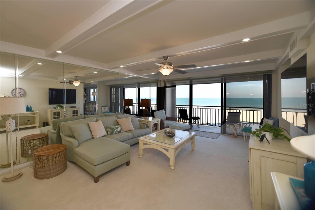 A living room with a sectional sofa, mirrored wall, and a balcony overlooking the ocean — 3820 GULF BOULEVARD UNIT 306, ST PETE BEACH, FL