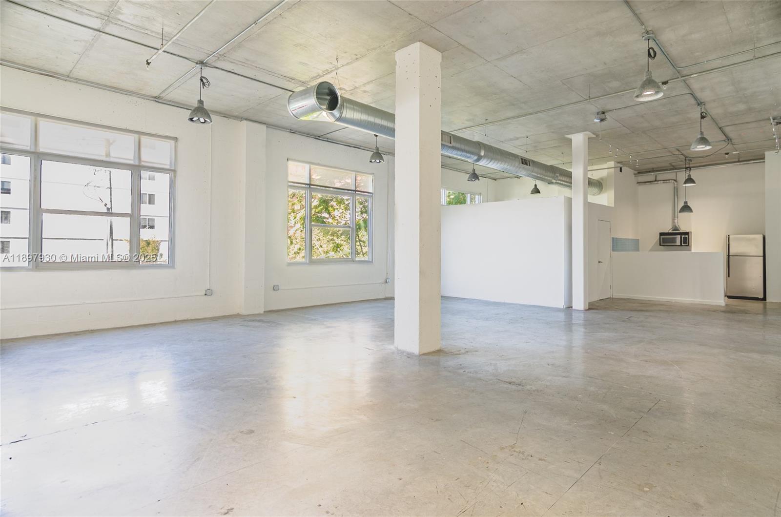 An open-plan industrial space features concrete floors, exposed ductwork, and large windows — 250 NW 23 # 202, Miami FL 33127, MIAMI, FL