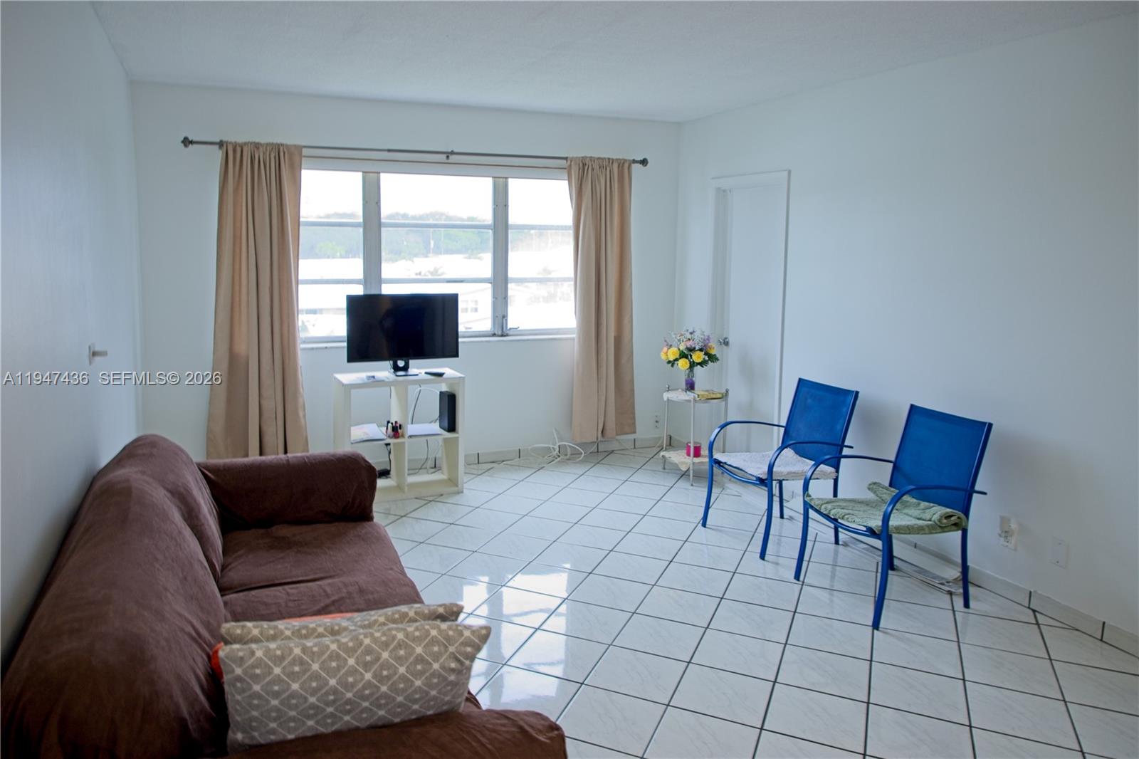 A living room features a brown sofa, two blue chairs, and tile flooring — 2309 Park Ln # 304, Hollywood FL 33021, HOLLYWOOD, FL