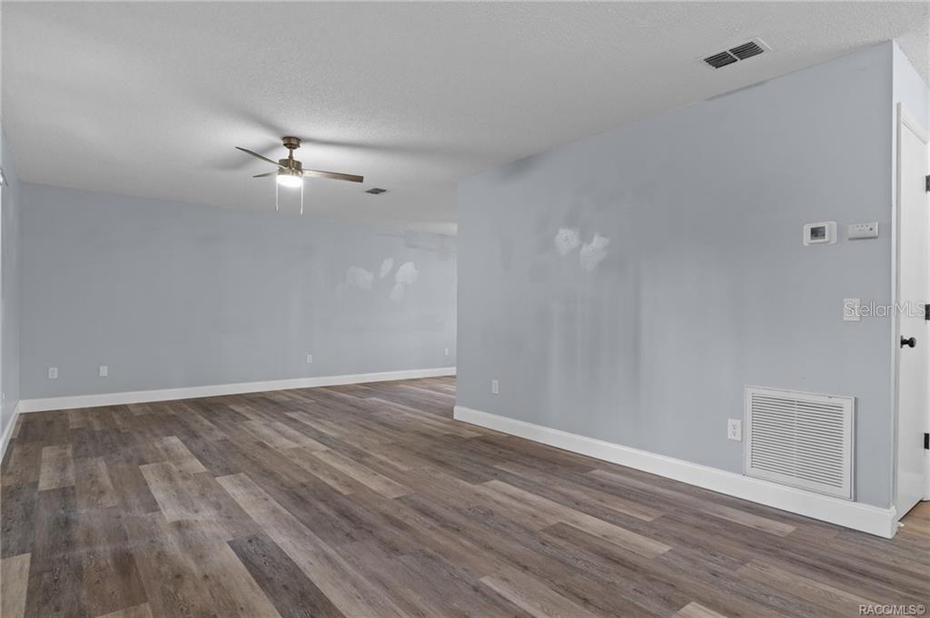 An empty room features light blue walls, wood-look flooring, and a ceiling fan — 1317 CARL STREET, INVERNESS, FL